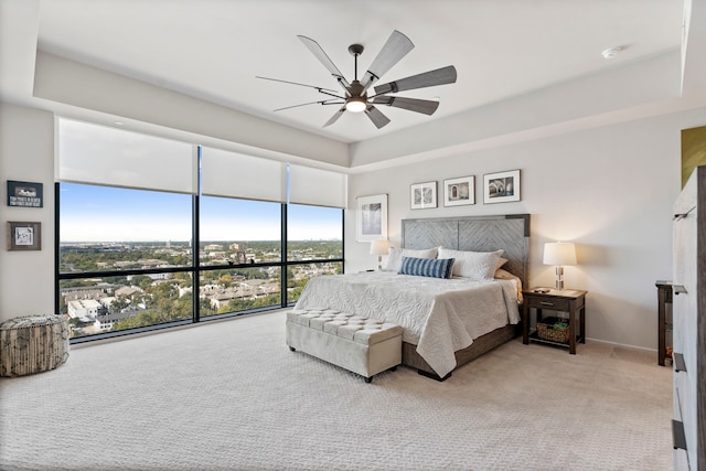 bedroom featuring ceiling fan, a raised ceiling, and carpet flooring