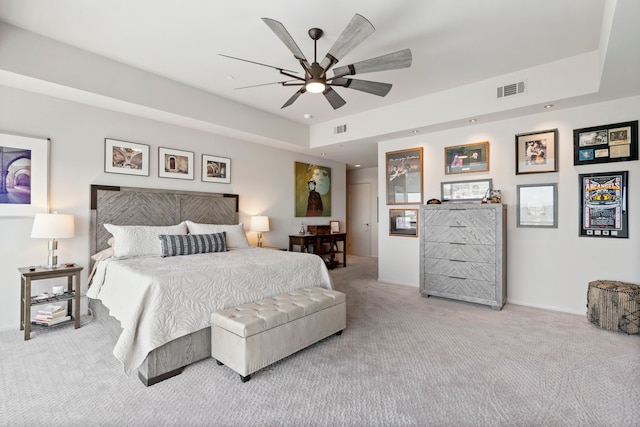 bedroom featuring a raised ceiling, carpet flooring, and ceiling fan