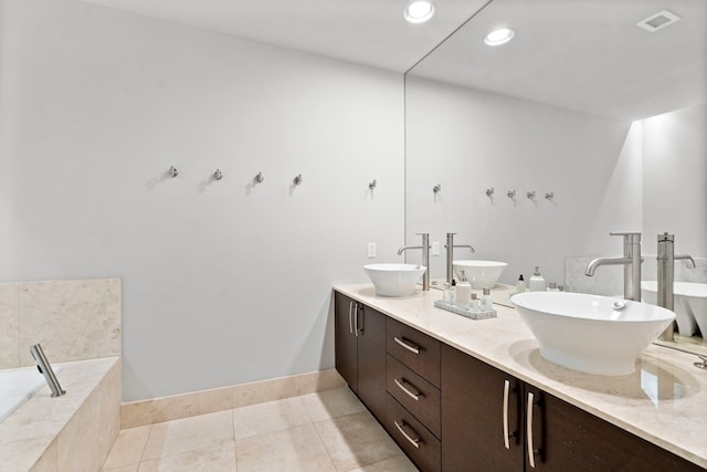 bathroom featuring vanity, a relaxing tiled tub, and tile patterned floors