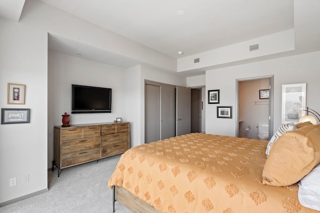 bedroom with a closet, light colored carpet, and connected bathroom