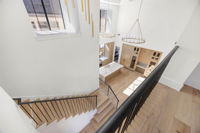 stairway with hardwood / wood-style flooring and a chandelier