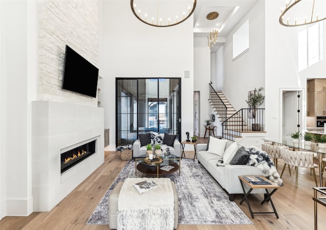 living room with a towering ceiling, light hardwood / wood-style floors, and a notable chandelier