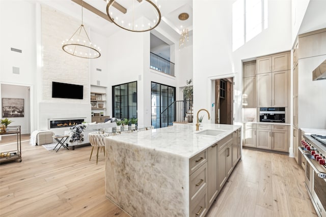 kitchen featuring a towering ceiling, a fireplace, light stone countertops, and sink