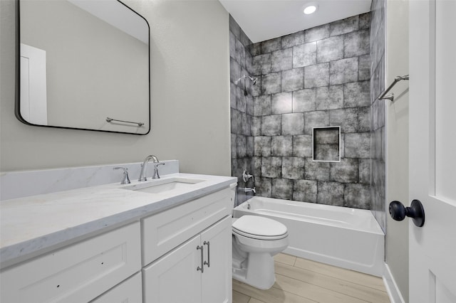 full bathroom with hardwood / wood-style flooring, toilet, vanity, and tiled shower / bath