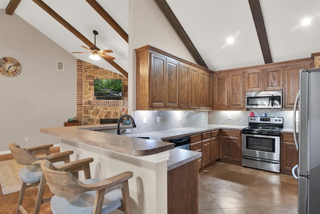 kitchen featuring beam ceiling, a breakfast bar, appliances with stainless steel finishes, and kitchen peninsula