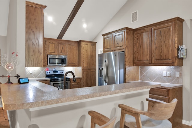 kitchen with lofted ceiling, kitchen peninsula, a kitchen bar, appliances with stainless steel finishes, and tasteful backsplash