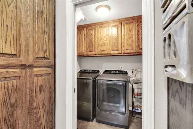 laundry room with light tile patterned floors, cabinets, and separate washer and dryer