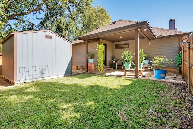 rear view of property with a yard, a patio area, and a storage unit