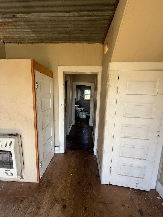 hallway featuring wood walls, heating unit, and dark hardwood / wood-style flooring