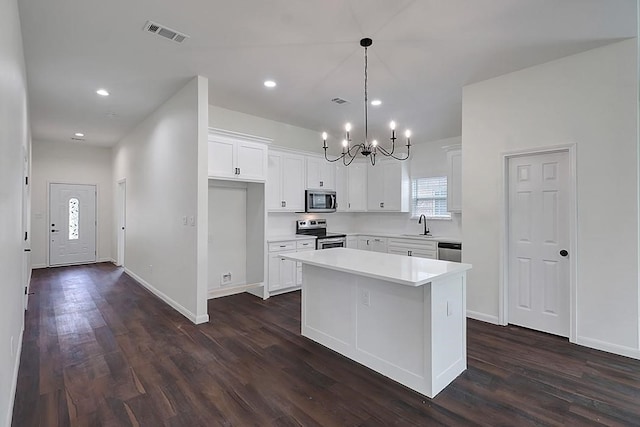 kitchen with dark wood-type flooring, hanging light fixtures, stainless steel appliances, a center island, and white cabinets