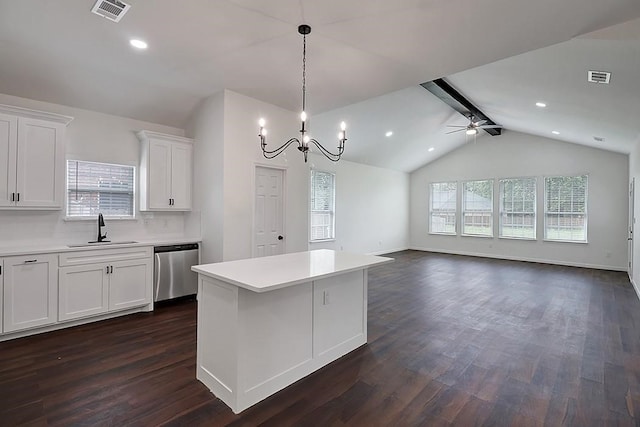 kitchen with vaulted ceiling with beams, dark wood-type flooring, a wealth of natural light, stainless steel dishwasher, and white cabinetry