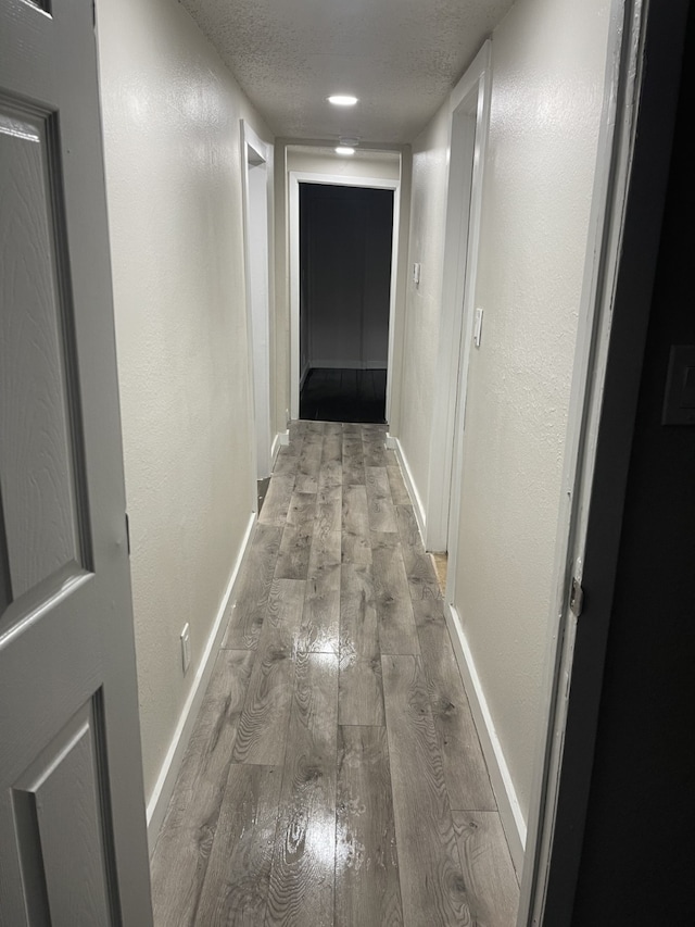 hall featuring a textured ceiling and light wood-type flooring