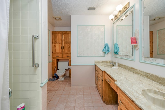 bathroom with a textured ceiling, toilet, walk in shower, vanity, and tile patterned flooring