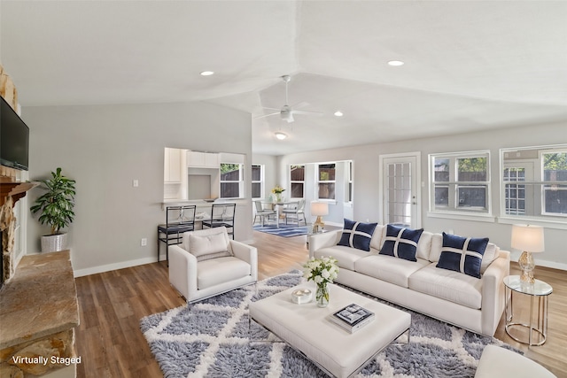 living room with ceiling fan, wood-type flooring, lofted ceiling, and a fireplace