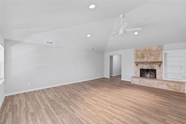 unfurnished living room featuring ceiling fan, light wood-type flooring, vaulted ceiling, built in shelves, and a stone fireplace