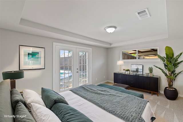 carpeted bedroom with french doors, access to outside, and a raised ceiling