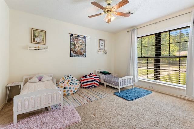 bedroom with ceiling fan, carpet, and a textured ceiling