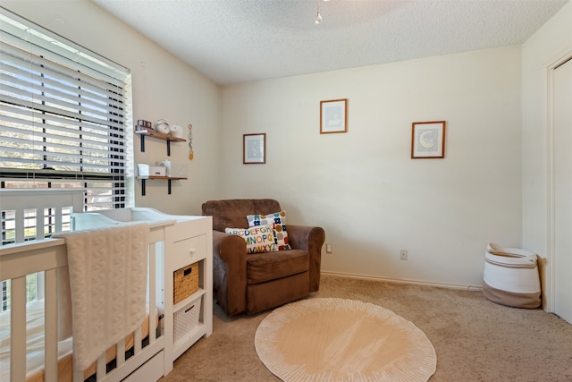 bedroom with light carpet, a textured ceiling, and a crib