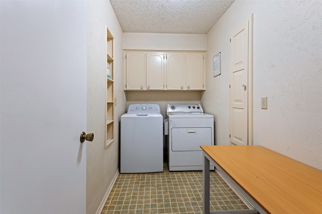 laundry area with washer and clothes dryer, a textured ceiling, and cabinets