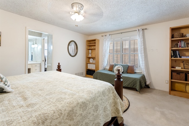 carpeted bedroom with a textured ceiling, ensuite bathroom, and ceiling fan