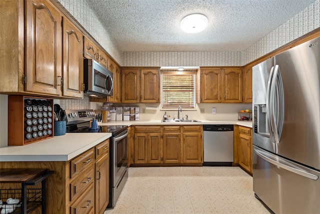 kitchen with appliances with stainless steel finishes, a textured ceiling, and sink