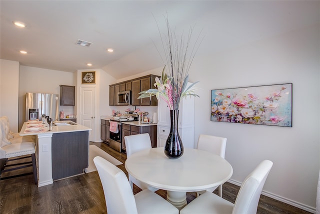 dining space featuring sink, vaulted ceiling, and dark hardwood / wood-style floors