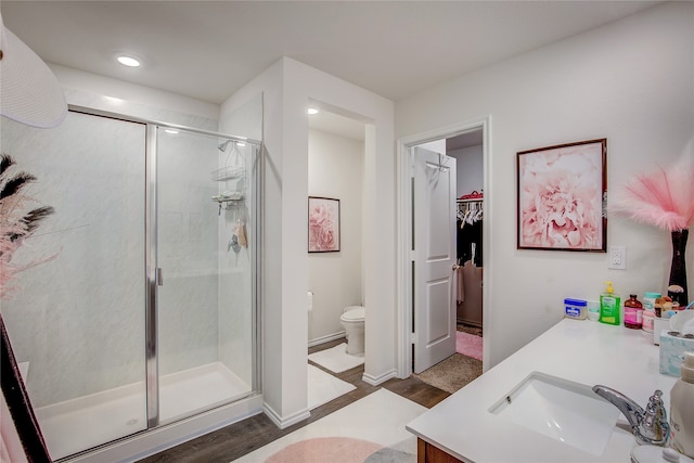 bathroom with toilet, an enclosed shower, hardwood / wood-style floors, and vanity