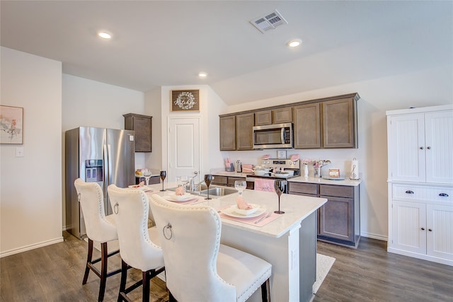 kitchen featuring a breakfast bar area, an island with sink, dark hardwood / wood-style floors, sink, and stainless steel appliances