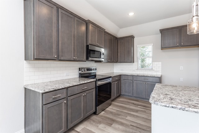 kitchen featuring decorative backsplash, hanging light fixtures, appliances with stainless steel finishes, light hardwood / wood-style flooring, and dark brown cabinetry