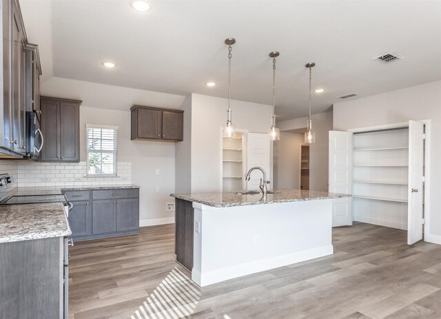 113 Bailey Ranch Dr, Lindsay, TX 76240 - kitchen with light wood-style floors, an island with sink, baseboards, a sink, and light stone counters