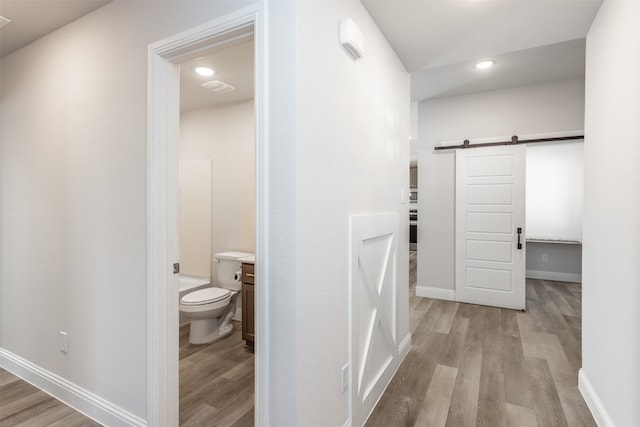 corridor with light hardwood / wood-style flooring and a barn door