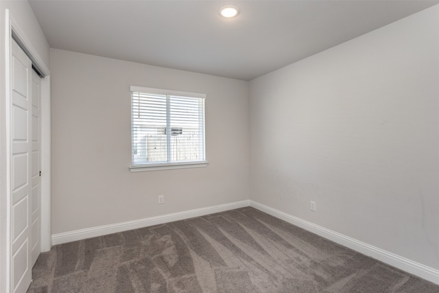 unfurnished bedroom with a closet and dark carpet