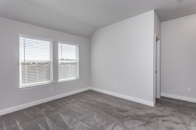 carpeted empty room featuring vaulted ceiling