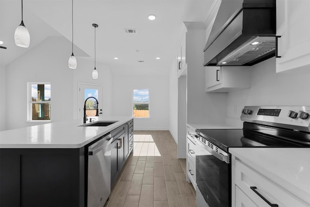 kitchen with stainless steel appliances, a center island with sink, custom exhaust hood, white cabinetry, and light hardwood / wood-style floors