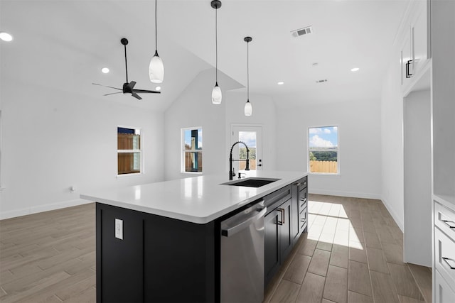 kitchen featuring an island with sink, sink, light wood-type flooring, stainless steel dishwasher, and white cabinets