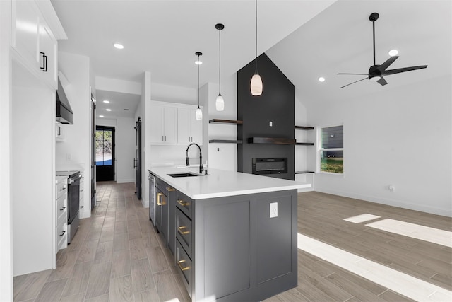 kitchen with light hardwood / wood-style flooring, an island with sink, sink, pendant lighting, and white cabinetry