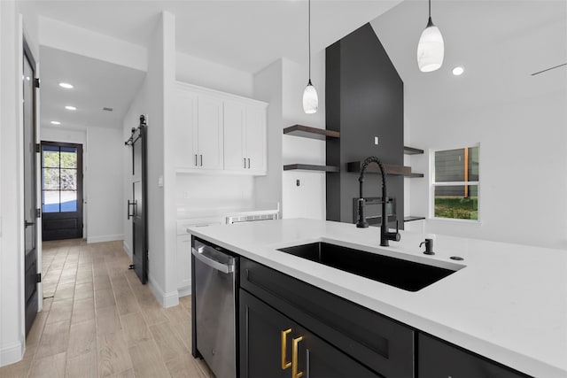 kitchen with dishwasher, sink, a barn door, pendant lighting, and white cabinetry