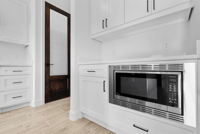 interior details with white cabinets and stainless steel microwave