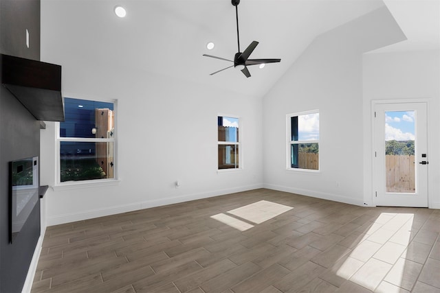 unfurnished living room with hardwood / wood-style flooring, high vaulted ceiling, and ceiling fan