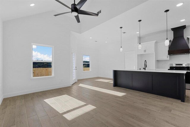 unfurnished living room featuring ceiling fan, high vaulted ceiling, light wood-type flooring, and plenty of natural light