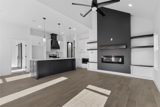 kitchen featuring custom exhaust hood, white cabinets, dark hardwood / wood-style flooring, a kitchen island with sink, and pendant lighting