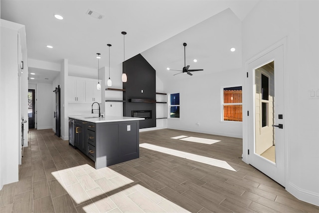 kitchen featuring a kitchen island with sink, sink, decorative light fixtures, white cabinetry, and dark hardwood / wood-style flooring