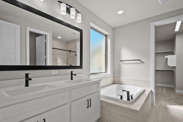 full bath featuring a bath, double vanity, a tile shower, and a sink