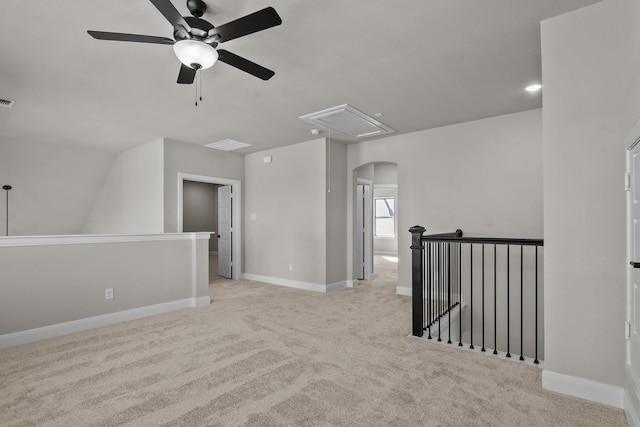 carpeted empty room with visible vents, arched walkways, attic access, and baseboards