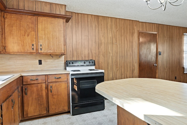 kitchen featuring electric range, a textured ceiling, and wood walls