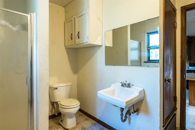 bathroom featuring sink, toilet, and a shower with shower door