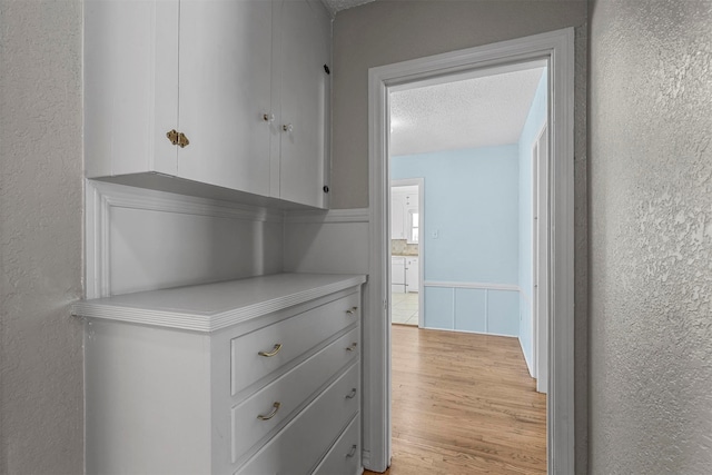 hallway featuring light hardwood / wood-style flooring and a textured ceiling