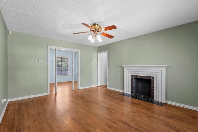 unfurnished living room with a tile fireplace, wood-type flooring, a textured ceiling, and ceiling fan