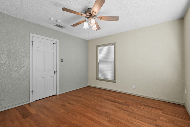 empty room featuring ceiling fan, hardwood / wood-style flooring, and a textured ceiling