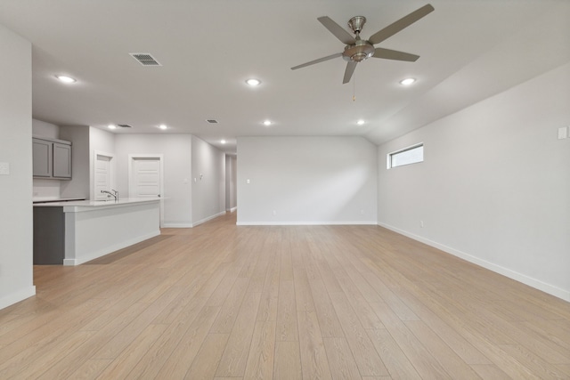 unfurnished living room with light hardwood / wood-style flooring, sink, and ceiling fan